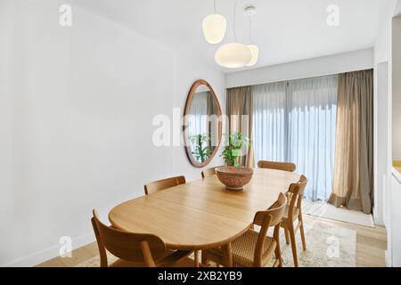 Salle à manger contemporaine au décor d'inspiration scandinave, lignes épurées et table ovale en bois avec chaises assorties Banque D'Images