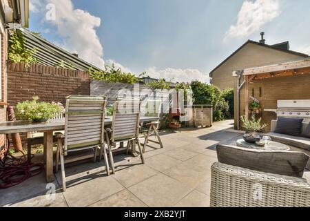 Un agréable patio extérieur à Rosendael, Amsterdam avec un coin repas avec des chaises en bois autour d'une table rustique, complété par un coin salon confortable Banque D'Images