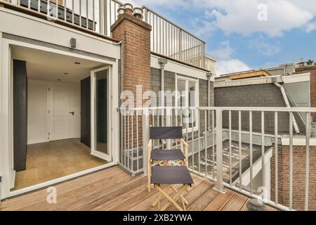 Un balcon urbain tranquille avec des éléments de design moderne, y compris une chaise pliante élégante, du parquet et une architecture classique en briques, parfait fo Banque D'Images