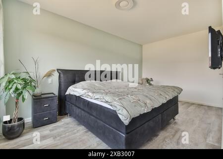 Une chambre contemporaine à Duintopstraat avec un élégant lit king-size avec une tête de lit moelleuse, flanquée de tables de nuit minimalistes et complétée Banque D'Images