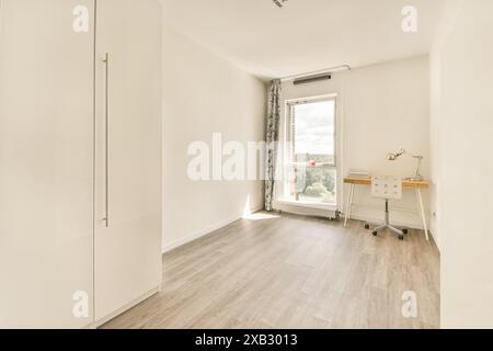 Chambre sereine au design minimaliste, éclairage naturel, bureau en bois et chaise confortable, idéale pour le travail et la détente. Banque D'Images