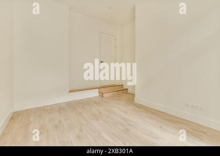 Une chambre vide et ensoleillée avec un design minimaliste, avec des murs blancs immaculés et un sol en bois chaleureux, attendant d'être remplie de meubles et de décoration. Banque D'Images