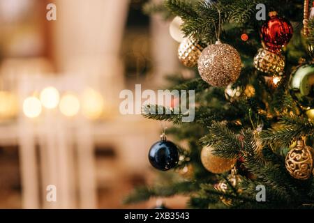 Gros plan d'un arbre de Noël décoré avec des jouets en verre vintage. Intérieur élégant et riche avec cheminée et bougies allumées. Décorations du nouvel an. Copier Banque D'Images