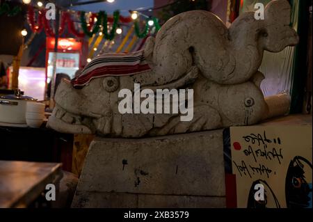 Dans les rues d'alfama pendant les festivités populaires des saints, une sculpture en pierre d'une créature mythique ressemblant à un poisson est ornée d'un chiffon de séchage Banque D'Images