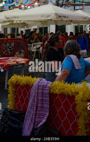 Femme avec une serviette drapée sur son épaule, travaillant à un stand de nourriture pendant les festivités populaires des Saints à Alfama Banque D'Images