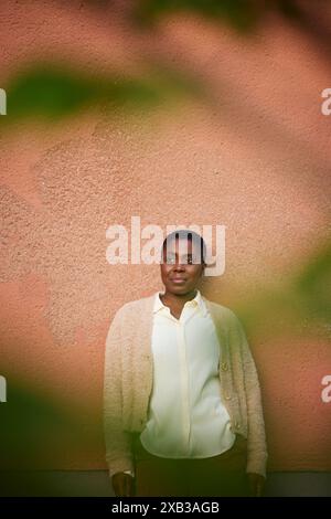 Femme mature contemplative debout contre le mur Banque D'Images