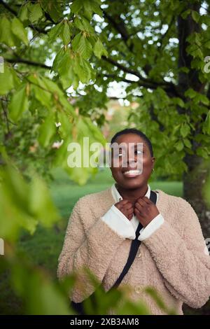 Femme mature souriante portant des vêtements chauds debout dans le parc Banque D'Images