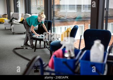 Concierge adulte nettoyant la table basse dans le hall Banque D'Images