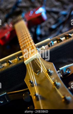 Une guitare électrique avec une finition Sunburst repose sur un ampli tube vintage à l'honneur. L'éclairage dramatique met en évidence les guitares creux-corps desig Banque D'Images