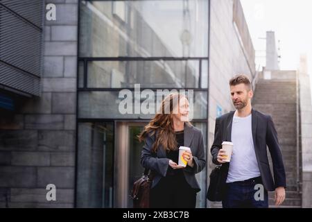 Heureux collègues féminins et masculins marchant contre la station de métro Banque D'Images