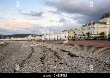 Les gens se promènent sur la promenade le long de l'architecture de bord de mer aux couleurs pastel à Llandudno, pays de Galles, au crépuscule Banque D'Images