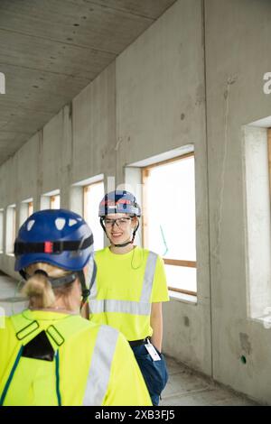 Souriante ingénieur civil discutant tout en se tenant debout sur le chantier de construction Banque D'Images