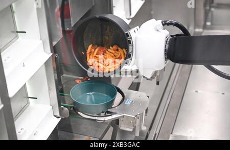 10 juin 2024, Bade-Württemberg, Tübingen : dans une cantine de l'hôpital universitaire de Tübingen, la nourriture est fraîchement préparée à la commande par un distributeur automatique. Selon l’hôpital universitaire, c’est le premier endroit au monde à utiliser le robot de cuisson de la start-up de Hambourg goodBytz. Cinq plats asiatiques, allemands et italiens sont proposés tous les jours, ainsi que des plats de Street food. Photo : Bernd Weißbrod/dpa Banque D'Images