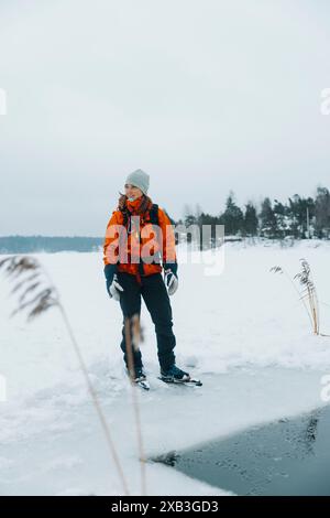 Femme portant des patins à glace et debout sur la neige près du lac gelé Banque D'Images