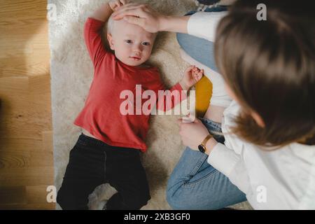 Directement au-dessus de la vue de la mère assise par son fils allongé sur la moquette à la maison Banque D'Images