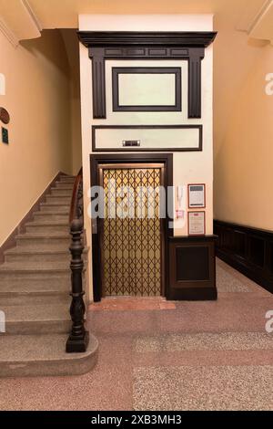 370 puits d'ascenseur et portes vintage-simulées au rez-de-chaussée entourés par les escaliers montants dans le hall d'un hôtel du centre historique. Camaguey-Cuba. Banque D'Images