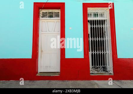 380 façade vert menthe et rouge de la maison coloniale dans la zone du centre historique montrant la fenêtre fréquente de grille à volets en bois, en forme de porte. Bayamo-Cuba. Banque D'Images