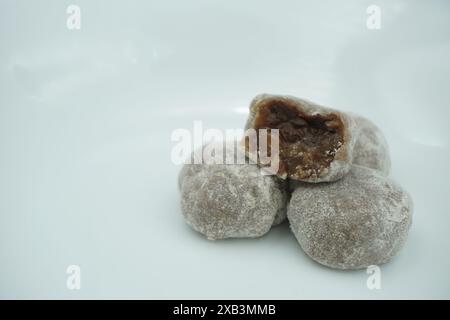 Mochi avec de la poudre blanche qui a été ouvert avec une garniture de chocolat et un fond blanc Banque D'Images
