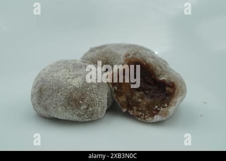 Mochi avec de la poudre blanche qui a été ouvert avec une garniture de chocolat et un fond blanc Banque D'Images