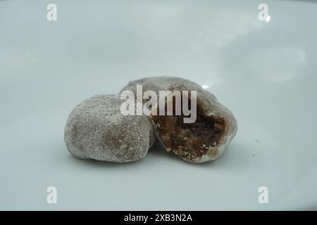 Mochi avec de la poudre blanche qui a été ouvert avec une garniture de chocolat et un fond blanc Banque D'Images