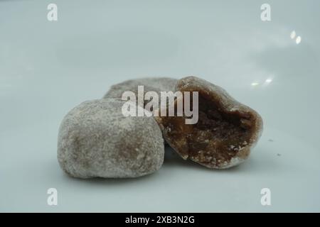 Mochi avec de la poudre blanche qui a été ouvert avec une garniture de chocolat et un fond blanc Banque D'Images