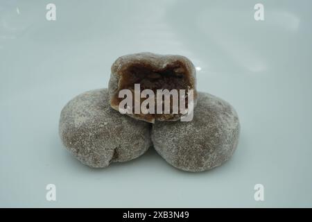 Mochi avec de la poudre blanche qui a été ouvert avec une garniture de chocolat et un fond blanc Banque D'Images