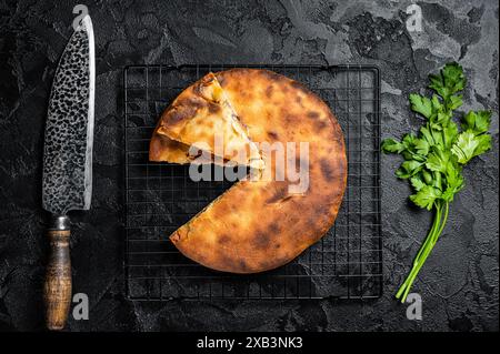 Tarte d'ossète cuite avec de la viande de boeuf et des herbes. Arrière-plan noir. Vue de dessus. Banque D'Images