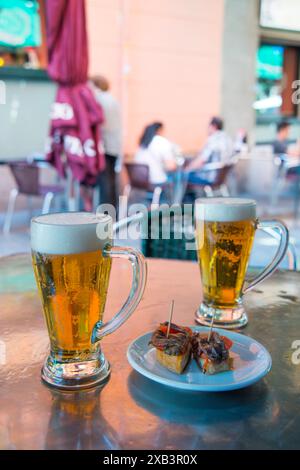 Apéritif espagnol : deux verres de bière avec tapa sur une terrasse. Madrid, Espagne. Banque D'Images