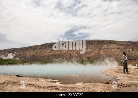 Guide touristique à Alolabad, en Éthiopie, montrant des sources naturelles volcaniques géothermiques chaudes avec piscine vapeur et petits lacs colorés, geysers et criques Banque D'Images