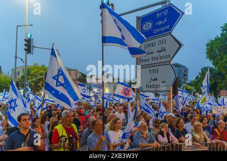 Haïfa, Israël - 08 juin 2024 : foule de personnes avec divers signes et drapeaux dans une Assemblée protester contre le gouvernement, appelant à de nouvelles élections. Banque D'Images