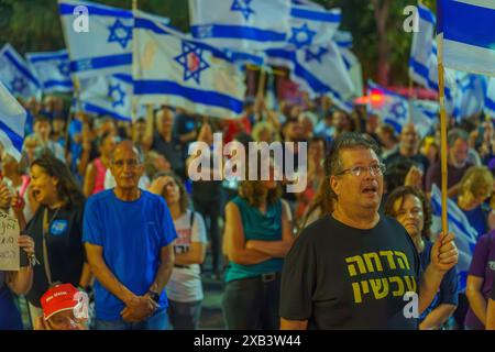 Haïfa, Israël - 08 juin 2024 : foule de personnes avec divers signes et drapeaux dans une Assemblée protester contre le gouvernement, appelant à de nouvelles élections. Banque D'Images