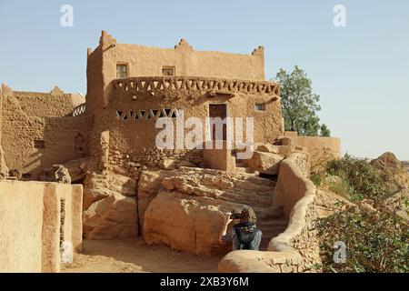 Touriste prenant une photo d'une maison en briques de boue dans le ksar de Taghit en Algérie Banque D'Images