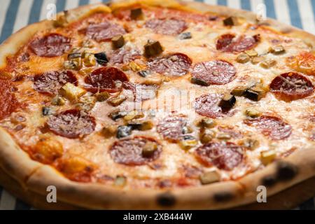 Pizza italienne avec saucisse pepperoni fumée, fromage parmesan et champignons sauvages dans une pizzeria sur la table Banque D'Images