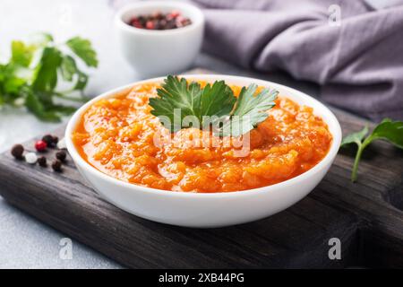 Caviar fait maison à partir de tomates courgettes et d'oignons dans une plaque de céramique, sur un fond gris. Conserves de production maison, conserves de légumes cuits en conserves Banque D'Images