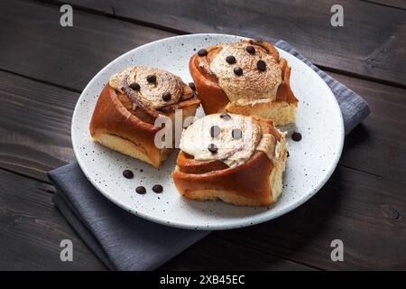 Kanelbulle petits pains à la cannelle avec crème au beurre sur une table en bois rustique. Pâtisseries fraîches faites maison Banque D'Images