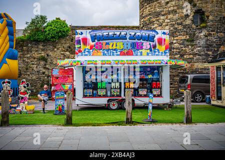 Conwy Wales UK 06-01-2024. Stand de slushie coloré à la foire extérieure avec des décorations vibrantes et un fond de mur de pierre historique Banque D'Images