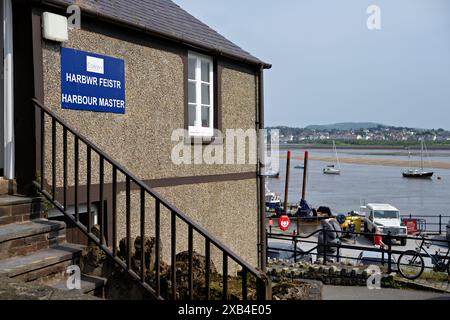 Conwy Wales UK 06-01-2024. Un bâtiment pittoresque de maître de port surplombant un port serein avec des bateaux et un paysage urbain lointain. Banque D'Images