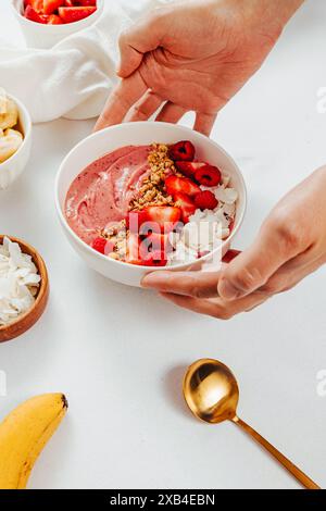 Mains masculines mettant un bol de smoothie d'été frais avec des fraises sur la table, vue rapprochée Banque D'Images