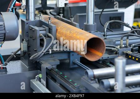 Découpe de tuyaux métalliques sur une scie à ruban horizontale automatique. Mise au point sélective. Banque D'Images