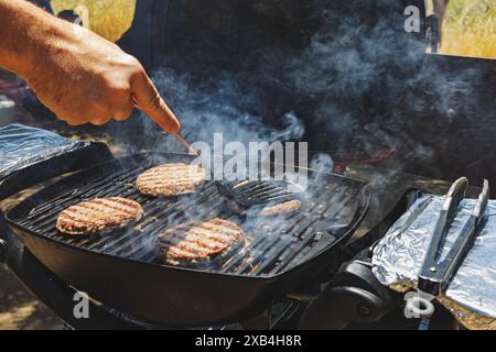 Gros plan des viandes de bœuf sur le gril, homme cuisinant des hamburgers à l'extérieur Banque D'Images