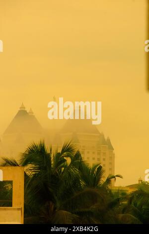 Cette photographie évocatrice capture un matin brumeux dans un paysage urbain, où un grand bâtiment aux toits pointus distinctifs émerge à travers un Banque D'Images