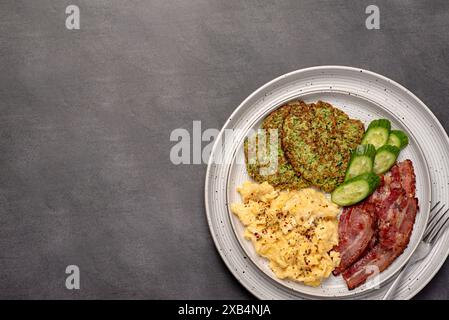 Photographie de nourriture vierge du petit déjeuner ; oeuf brouillé ; frit ; croustillant ; bacon, courgettes, crêpes à courgettes, concombre ; assaisonnement, brunch Banque D'Images