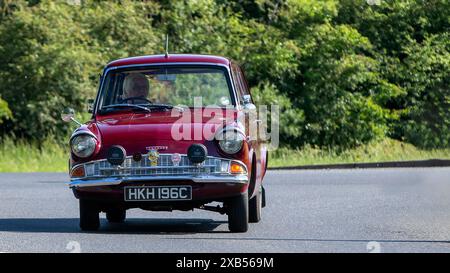 Stony Stratford, Royaume-Uni - 2 juin 2024 : 1965 marron Ford Anglia Estate voiture conduisant sur une route de campagne britannique Banque D'Images