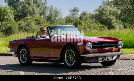 Stony Stratford, Royaume-Uni - 2 juin 2024 : 1973 Red Triumph TR6 voiture de sport britannique classique conduisant sur une route de campagne britannique Banque D'Images