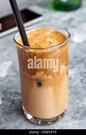 Délicieux café glacé dans Un verre avec gros plan sur la paille. Gros plan d'un café glacé rafraîchissant dans un verre avec une paille. Le mélange de café crémeux est parfait Banque D'Images