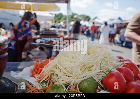 Marché extérieur, présentant une vue rapprochée des légumes et ingrédients frais. Le premier plan présente des légumes râpés, des citrons verts et des tomates mûres. Banque D'Images