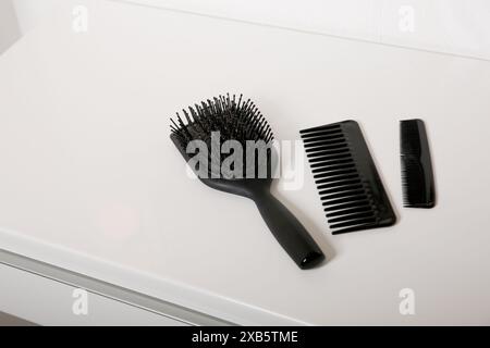 Brosse à cheveux et peignes utilisés avec quelques cheveux sur la table blanche, hygiène de la peau de la tête Banque D'Images