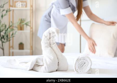 Femme de chambre faisant lit dans la chambre d'hôtel, se concentrer sur les serviettes Banque D'Images