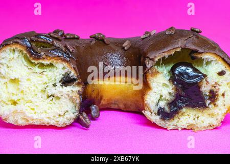 Gros plan d'un demi beignet en chocolat sur un fond violet. Banque D'Images