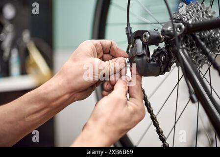 Mécanicien de vélo méconnaissable assemblant le système de freinage et de changement de vitesse d'un vélo dans le cadre du service d'entretien qu'il effectue dans son atelier. Réel Banque D'Images